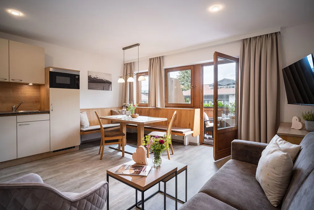 Modern eingerichtetes Wohnzimmer mit Küche und Balkon in einem alpinen Stil.