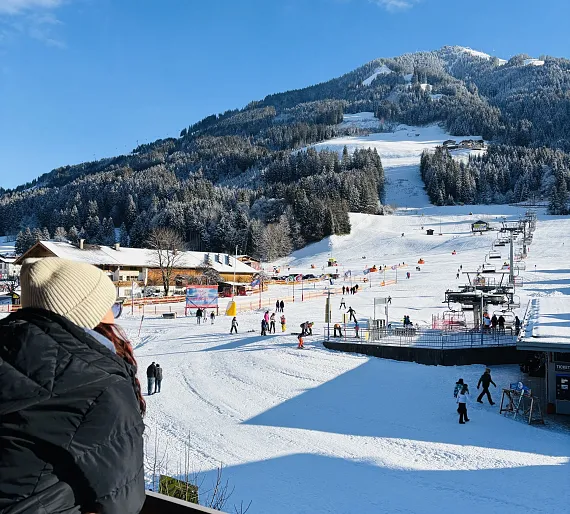 Verschneite Skiregion in Kitzbühel, Tirol mit Skilift und Skifahrern auf der Piste.