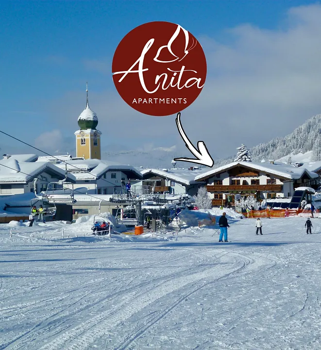 Winterliches Skigebiet in Tirol mit Apartments und beschneiten Gebäuden.