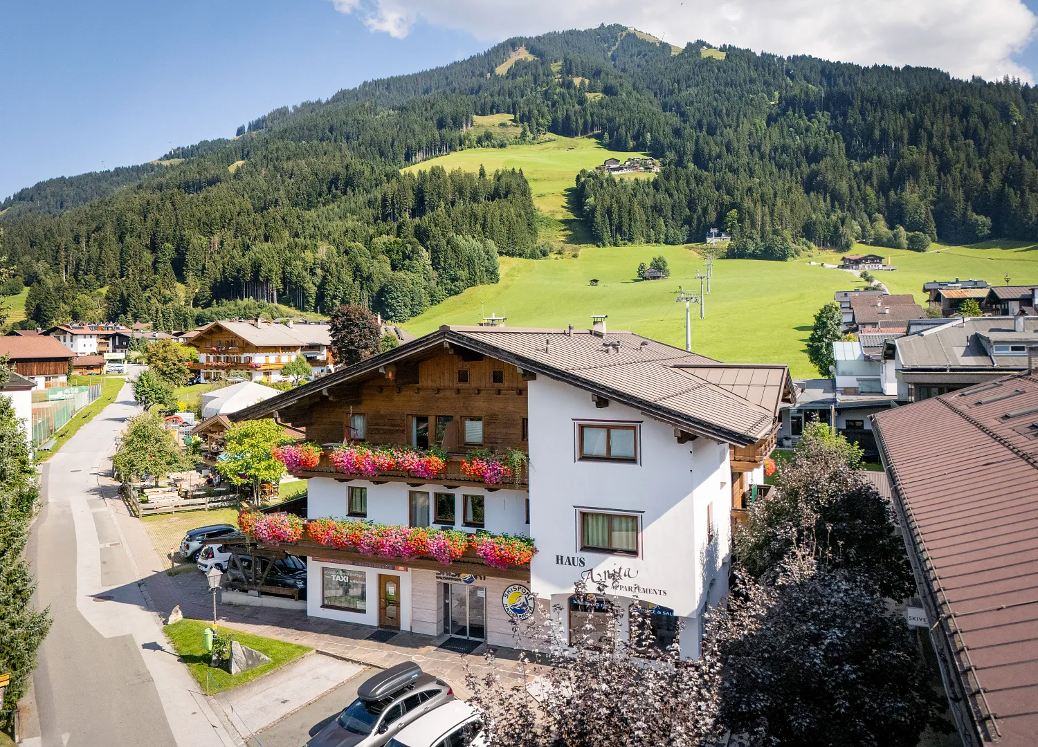 Alpenhaus mit Blumendekoration, umgeben von grünen Wiesen und Bergen, in Tirol, Kitzbühel.